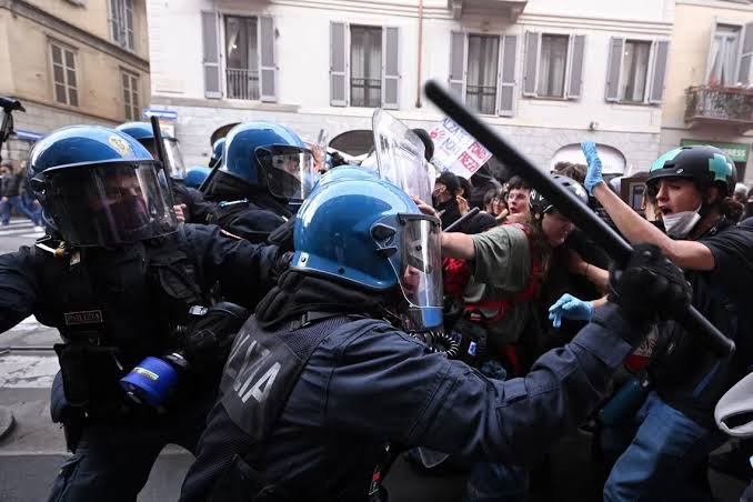 Italian Woman Confronts Police While Rioter Throws Explosive During Milan Clashes
